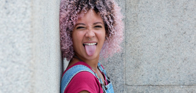 Mädchen mit rosa Harren streckt die Zunge heraus