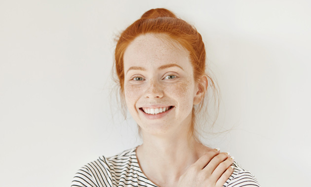 Stylish freckled teenage girl with hair knot having fun